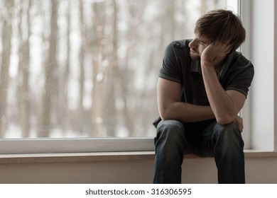 Young miserable depressed man sitting and thinking