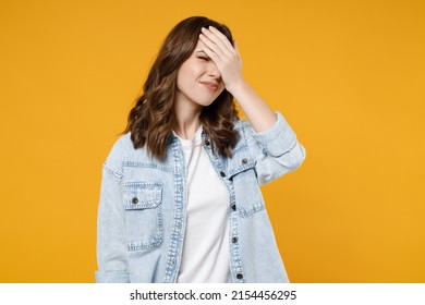 Young mistaken confused disappointed stressed sad woman 20s wearing stylish casual denim shirt white t-shirt put hand on face facepalm epic fail gesture isolated on yellow background studio portrait.