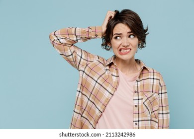 Young mistaken sad puzzled woman 20s wearing casual brown shirt look aside scratch hold head say oops isolated on pastel plain light blue color background studio portrait. People lifestyle concept.
