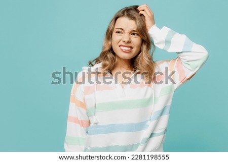 Young mistaken troubled confused sad dissatisfied blonde woman wear hoody look aside hold scratch head say oops isolated on plain pastel light blue cyan background studio portrait Lifestyle concept