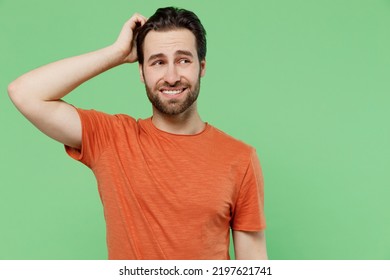 Young mistaken worried sad caucasian man 20s wear casual orange t-shirt look aside scratch hold head isolated on plain pastel light green color background studio portrait. People lifestyle concept. - Powered by Shutterstock