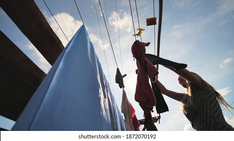 The Young Mistress Hangs Her Laundry Outdoors On A Sunny Day.