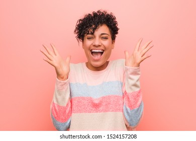 Young mixed african american teenager woman celebrating a victory or success, he is surprised and shocked.