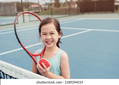 Young mixed Asian girl tennis beginner player on outdoor blue court, kid active sport