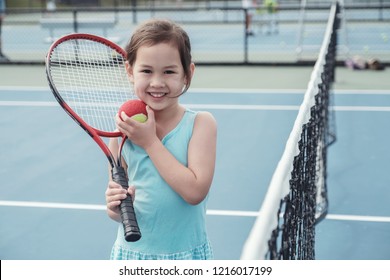 Young mixed Asian girl tennis beginner player on outdoor blue court