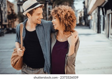 Young mixed couple embracing each other while having a stroll in the city - Powered by Shutterstock