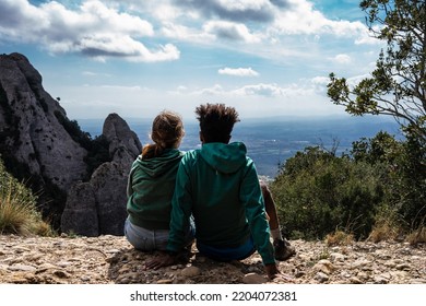 Young Mixed Couple Watching A View From The High Point Of A Mountain 