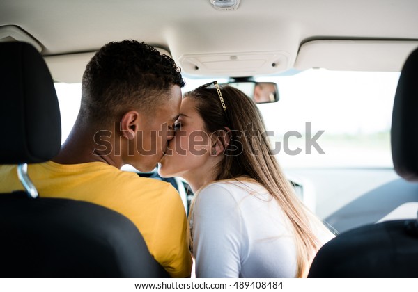 Young\
mixed ethnic couple kissing in car - rear\
view