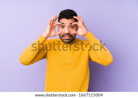 Young mixed race arabic man isolated keeping eyes opened to find a success opportunity.