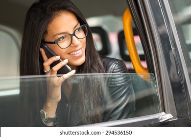 Young Mixed Race Businesswoman Portrait Inside A Taxi In Canary Wharf Area In London Talking At The Phone.