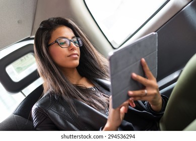 Young Mixed Race Businesswoman Portrait Inside A Taxi In Canary Wharf Area In London While Using A Tablet.