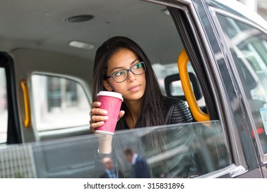 Young Mixed Race Businesswoman Portrait Inside A Taxi In Canary Wharf Area In London While Drinking A Cup Of Coffee.