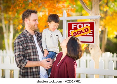 Young Mixed Race Chinese And Caucasian Family In Front Of Sold For Sale Real Estate Sign And Fall Yard.