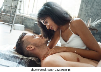 Young mixed race couple boyfriend and girlfriend at home lying on bed on plaid blanket looking at each other smiling happy close-up