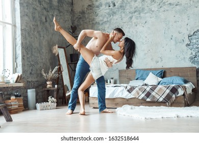 Young Mixed Race Couple Boyfriend Holding Girlfriend's Hip Bending Forward Dancing In Bedroom At Home Smiling Happy Before Kiss