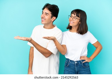 Young Mixed Race Couple Isolated On Blue Background Pointing Back And Presenting A Product