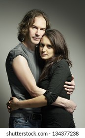 Young Mixed Race Couple Looking Sad And Thoughtful Cuddling On Plain Background