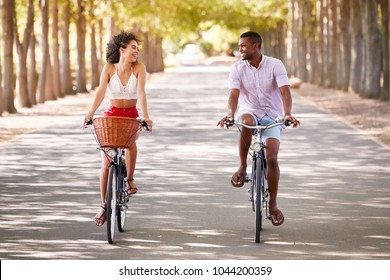 Young mixed race couple riding bicycles looking at each other