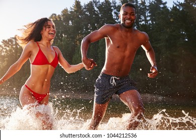 Young Mixed Race Couple Running And Splashing In A Lake