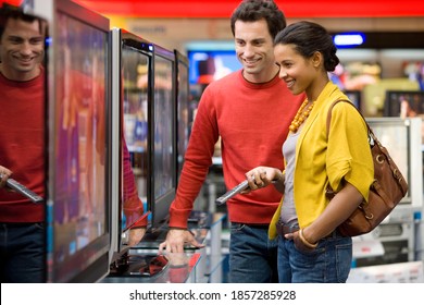 Young Mixed Race Couple Standing In The Middle Of An Electronics Appliances Store And Shopping For A New Television