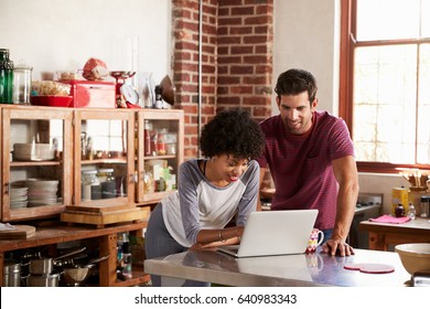 Young Mixed Race Couple Using Computer In Kitchen