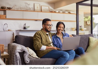 Young mixed race couple watching movie on laptop while relaxing on a weekend at home. Smiling indian man and beautiful woman sitting on sofa while using laptop and surfing the net. - Powered by Shutterstock