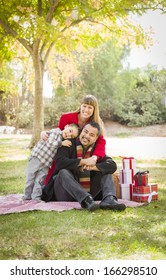 Young Mixed Race Family Enjoying Christmas Gifts In The Park Together.