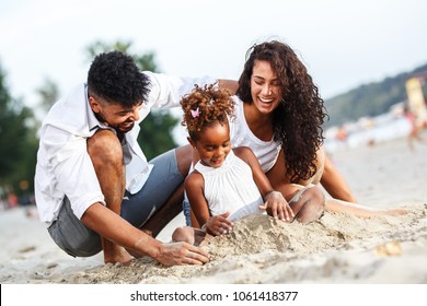 Young mixed race family sitting and relaxing at the beach on beautiful summer day.Playing in the sand.