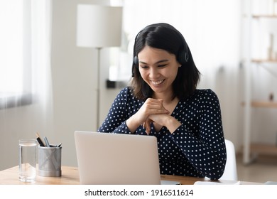 Young mixed race female in bluetooth headset have nice talk conversation via pc webcam. Friendly asian woman english language tutor give remote lesson before computer screen teaching pupil on distance - Shutterstock ID 1916511614