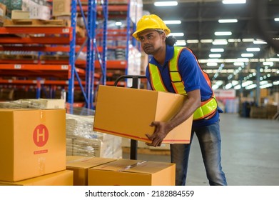 A Young mixed race male worker wearing helmet lifting cardboard box in warehouse, machinery and Logistics concept.  - Powered by Shutterstock