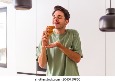 Young mixed race man eating croissant in a kitchen on the morning - Powered by Shutterstock