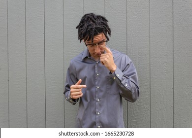 Young Mixed Race Man Looking Down Rubbing Eye, Furrowed Brow, Glasses, Natural Hair In Dreadlocks, Horizontal Aspect