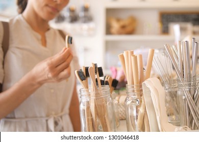 Young Mixed Race Woman Choosing Bamboo Eco Friendly Biodegradable Toothbrush in Zero Waste Shop. No plastic Conscious Minimalism Vegan Lifestyle. Reduce Reuse Recycle Concept.