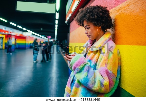 Young mixed race woman indoor\
metro station using smartphone surfing web shopping online or\
texting