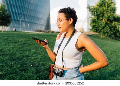 Young mixed race woman outdoor using smartphone watching video or recording vocal message