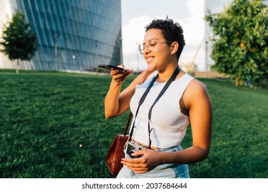 Young mixed race woman outdoor recording vocal message holding smartphone