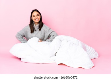 Young Mixed Race Woman Wearing Pijama Sitting On The Floor Posing With Arms At Hip And Smiling