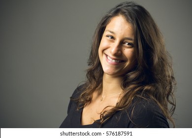 Young mixed race woman wearing a black t shirt and jeans stands in three quarters profile  while smiling at viewer - Shutterstock ID 576187591