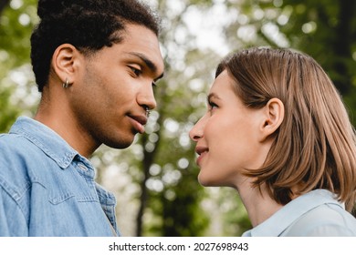 Young Mixed-race Couple Going To Kiss Each Other Walking In City Park On Romantic Date Together. Love At First Sight, First Love, True Feelings Relationship Concept