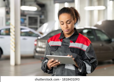 Young Mixed-race Female Technician Of Contemporary Car Service Touching Display Of Digital Tablet While Reading Online Questions Of Clients