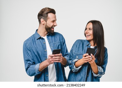Young mobile users, loving couple spouses girlfriend and boyfriend using smart phones together looking at each other, surfing on internet online, e-commerce, e-banking isolated in white background