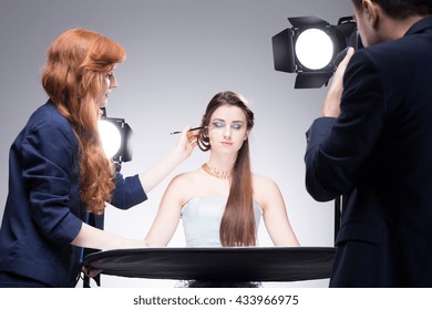 Young Model Having Her Strong Makeup Finished During Shooting A Portrait Photo In A Studio