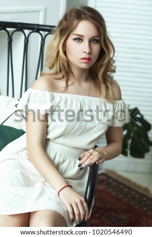 Young model is posing in a studio wearing white dress