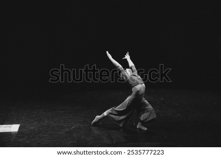 young modern ballet dancer posing in studio on black background, monochrome