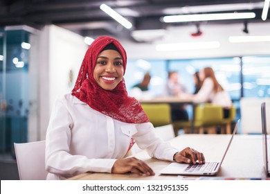 Young modern black muslim business woman wearing a red hijab,working on laptop computer in startup office. Diversity, multiracial concept - Powered by Shutterstock