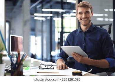 Young modern business man working using digital tablet while sitting in the office - Powered by Shutterstock