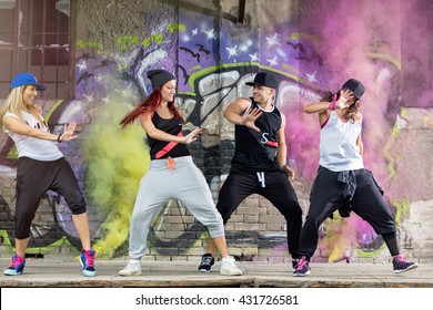 Trẻ hiện đại nhảy nhóm thực hành nhảy múa ở phía trước bức tường đầy màu sắc