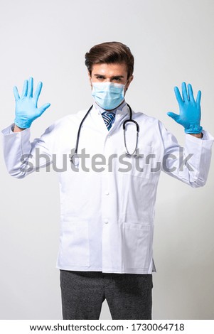 young and modern doctor in medical uniform wearing or fixing his steril gloves, isolated on white