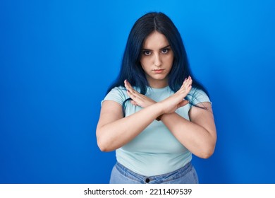 Young Modern Girl With Blue Hair Standing Over Blue Background Rejection Expression Crossing Arms Doing Negative Sign, Angry Face 