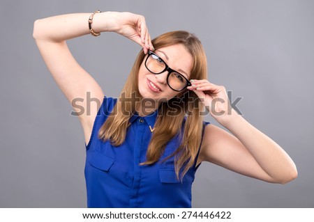 Young modern girl of european appearance with glasses. She holds her hands his glasses on his face. Woman wearing glasses. Girl student. Near person has space for text. Clever girl American. Have fun.